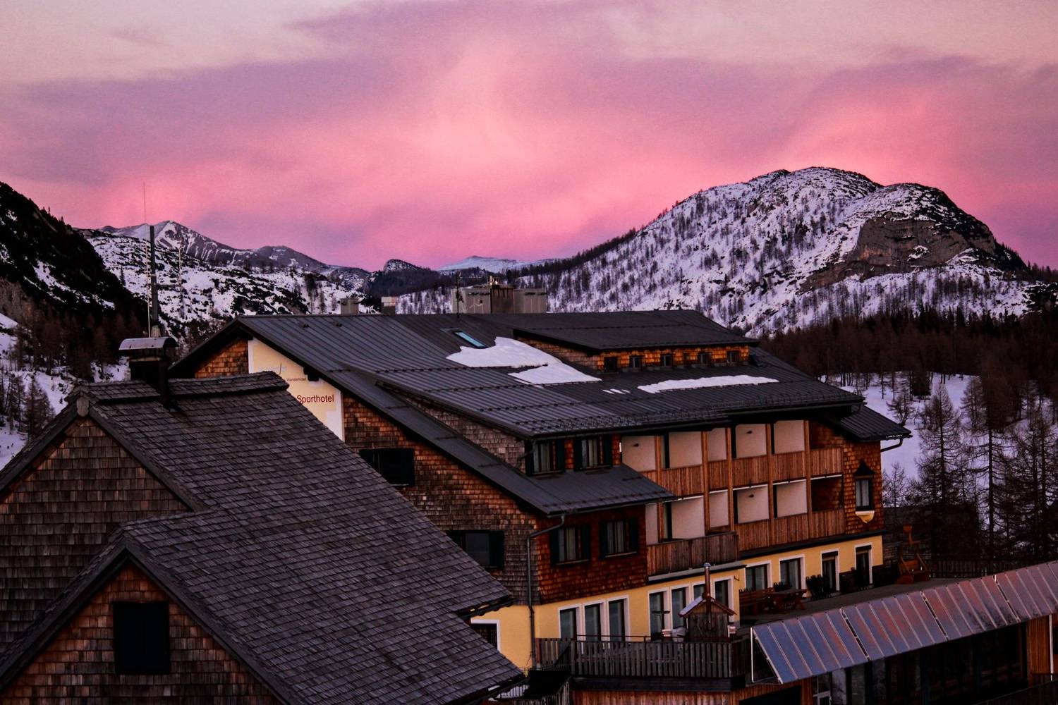 Beautiful mountain lodge with snow and pink sky at dusk, creating a serene winter scene.