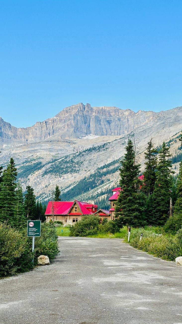 Picturesque mountain lodge with red roofs nestled in a scenic summer landscape with clear blue skies.