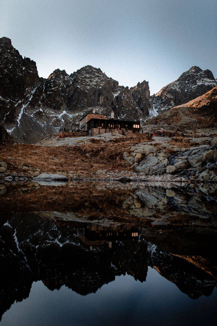 A tranquil mountain lodge reflecting in a lake in Vysoké Tatry, Slovakia.