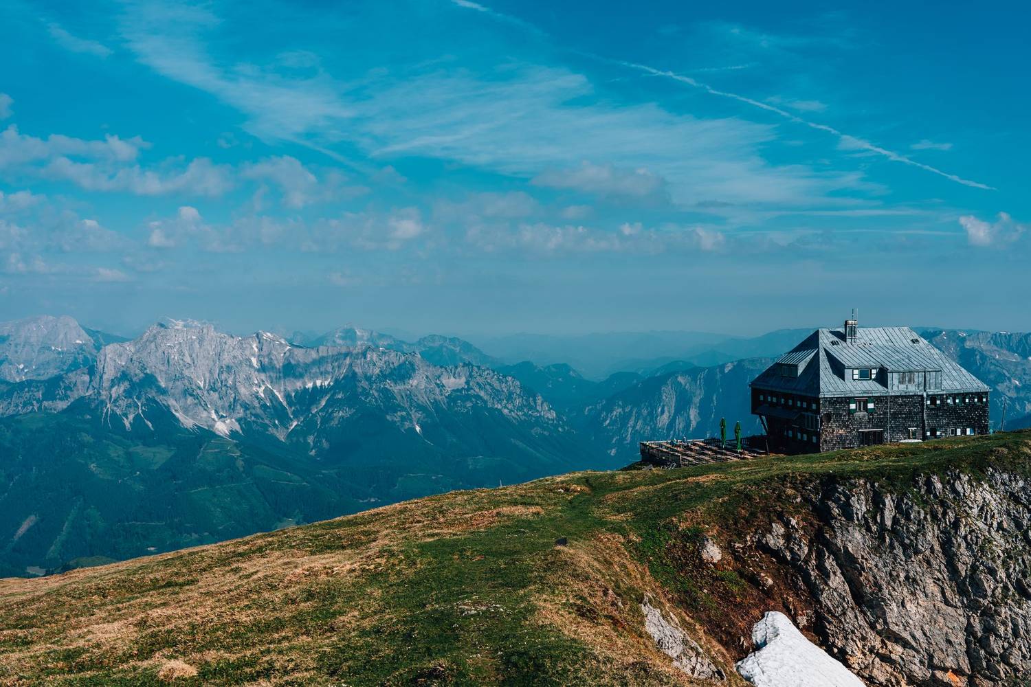 Breathtaking view of a lodge perched on a mountain top in Eisenerz, Austria, with stunning mountain ranges.