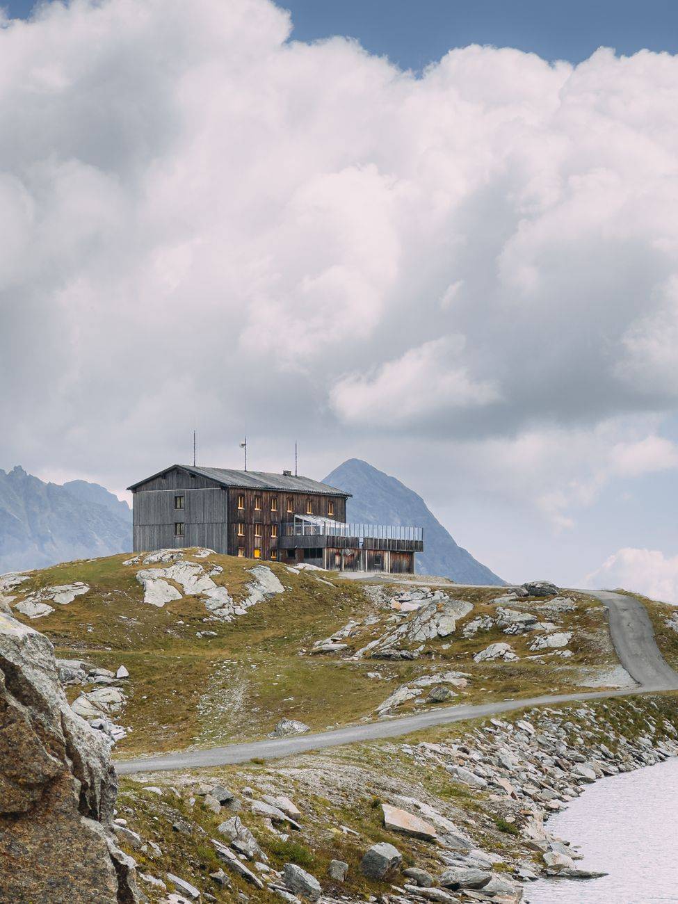 A scenic rustic lodge perched on a mountain slope beneath cloudy skies.