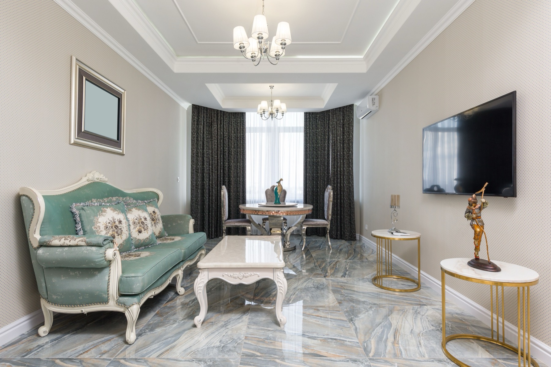 An elegant salon with a carved sofa, marble floor, chandelier and brass side tables